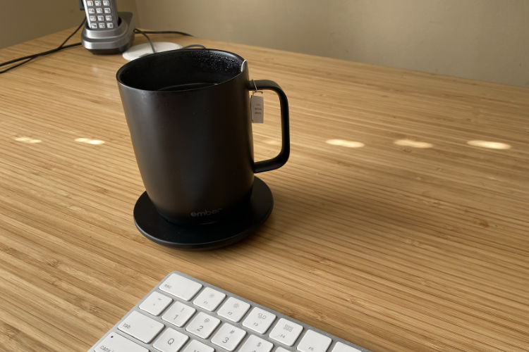 Ember Mug2 on a wood desktop, near a Mac keyboard