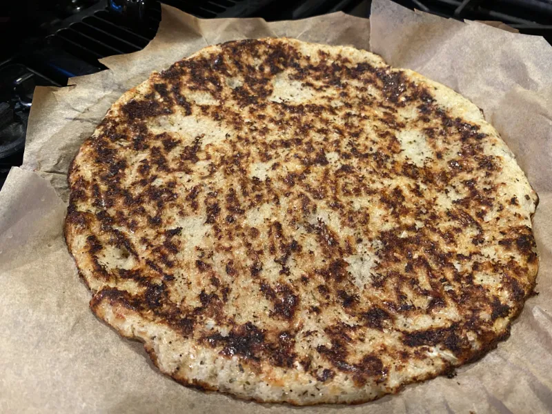 A cooking cauliflower pizza crust after cooking the second side